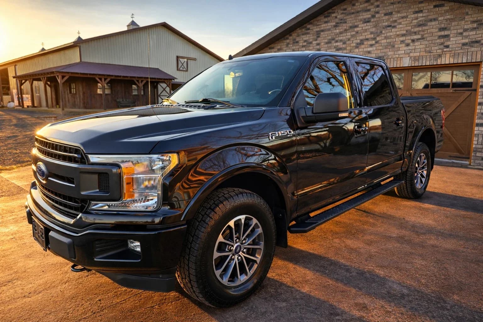 A black Ford F-150 parked outside the Ignite Motor Company shop at sunset